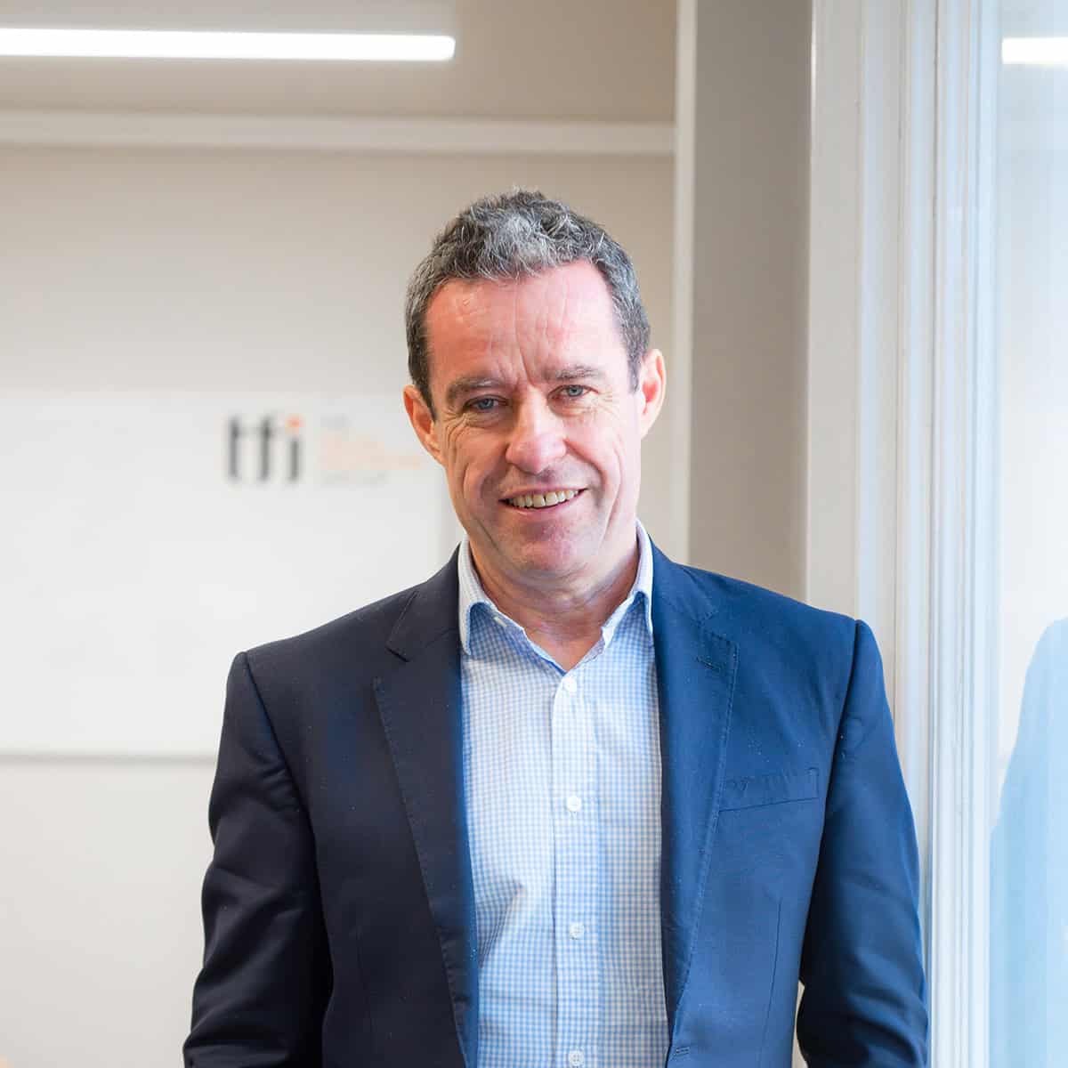 Business professional smiling in modern office setting with natural light.