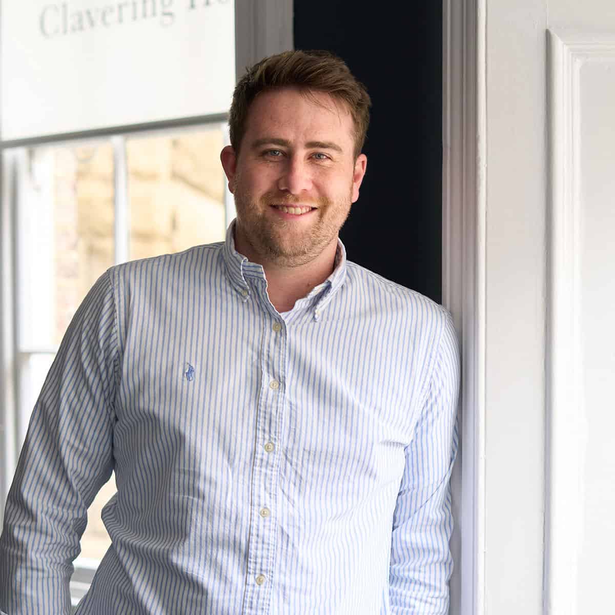 Professional man standing beside window at TFI, highlighting expert leadership and management skills.